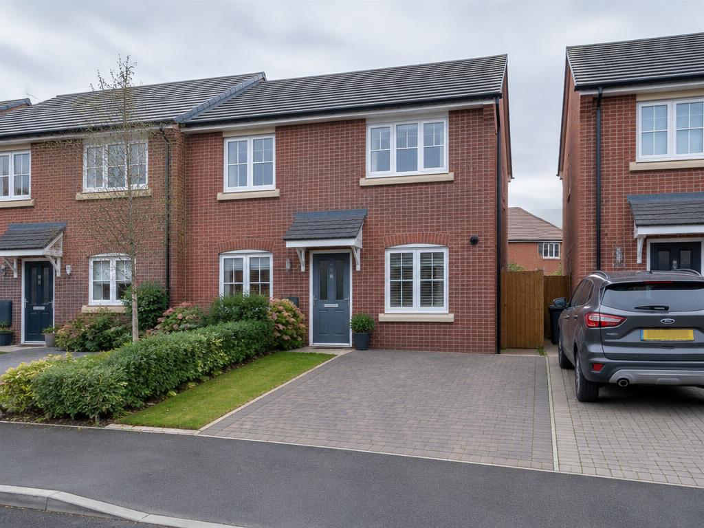 Modern red-brick UK townhouse exterior with driveway on a quiet residential street